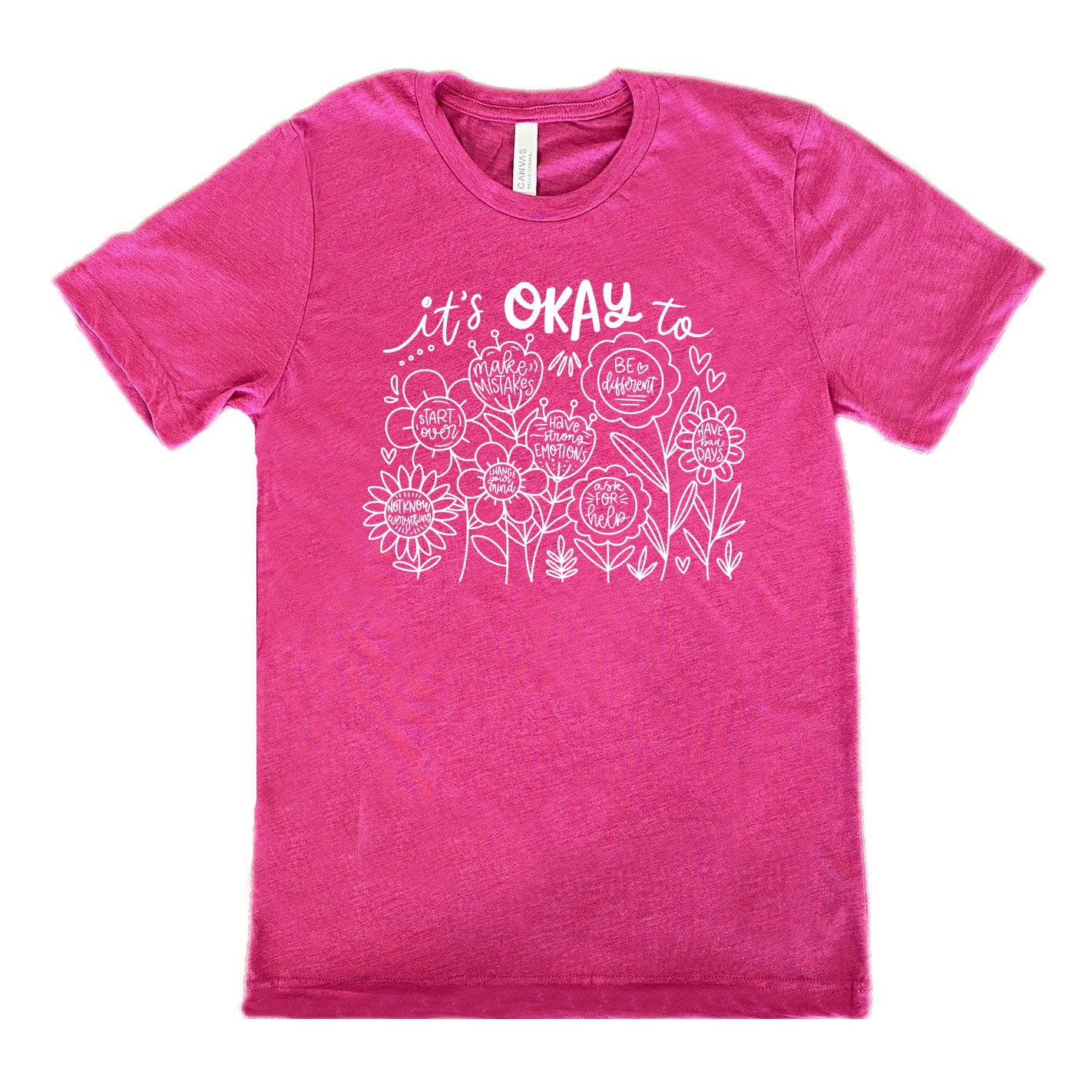 berry unisex tee with the words "it's okay to" on it, and underneath there are many flowers that each have the completion of that phrase; the different endings are "make mistakes", "be different", "have bad days", "ask for help", "have strong emotions", "change your mind", "Start over", and "not know everything".