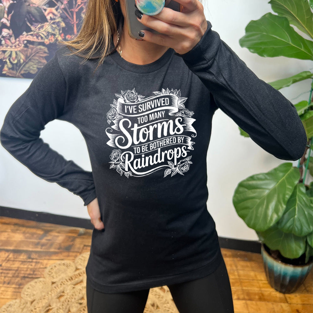 Heather Black Long Sleeve, with wording I've Survived Too Many Storms to be Bothered by Raindrops, with banners and flowers