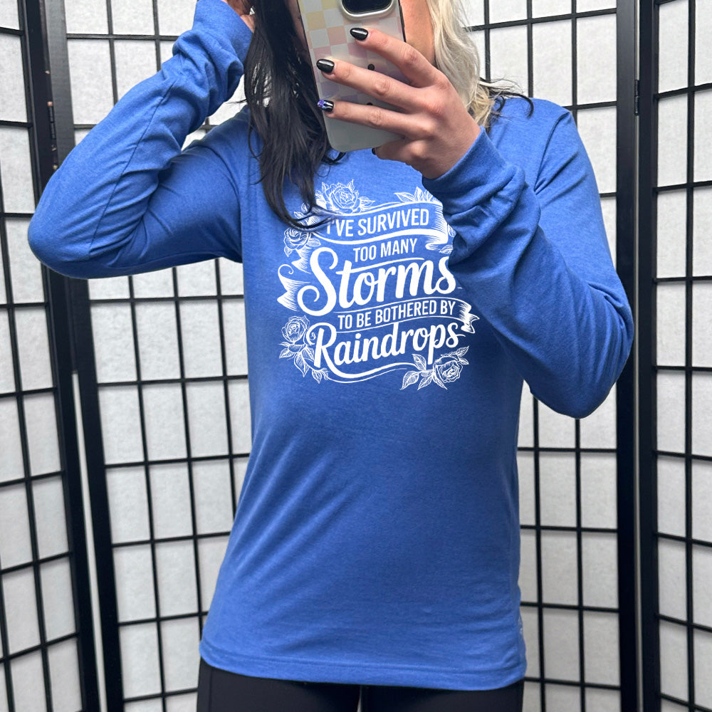 Heather True Royal Long Sleeve, with wording I've Survived Too Many Storms to be Bothered by Raindrops, with banners and flowers