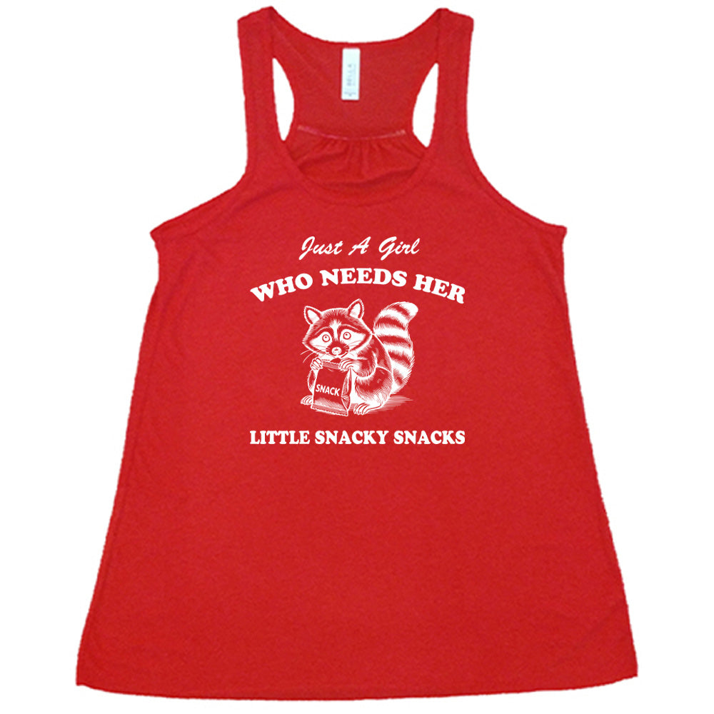 Red colored flowy tank with a raccoon holding a snack graphic on it that says "Just a Girl Who Needs Her Little Snacky Snacks"