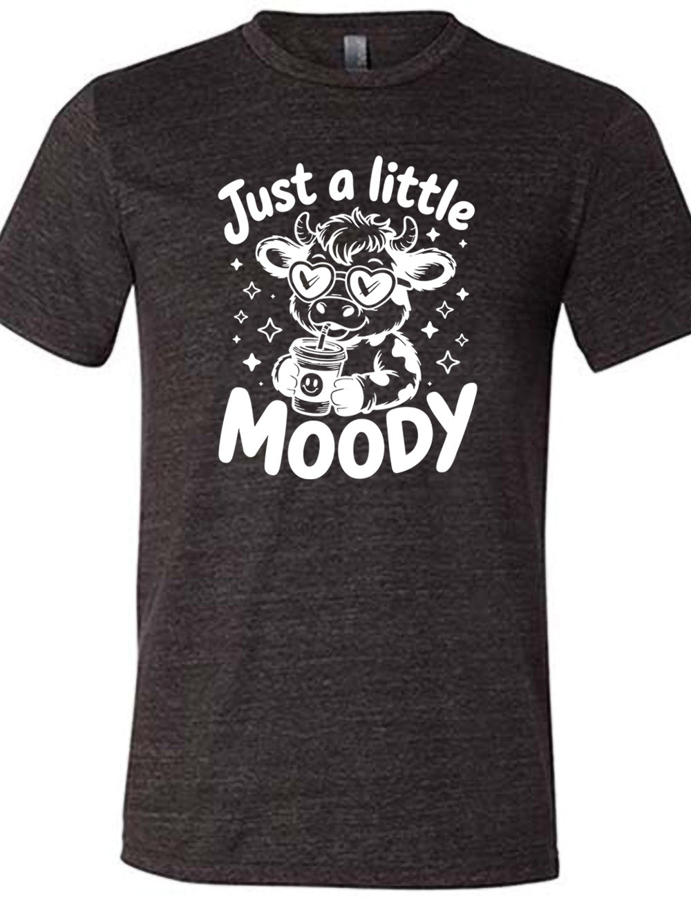 black unisex tee with the graphic of a cartoon cow, wearing heart sunglasses and drinking out of an iced cup with a straw, surrounded by little stars, as well as the words "just a little moody" around it