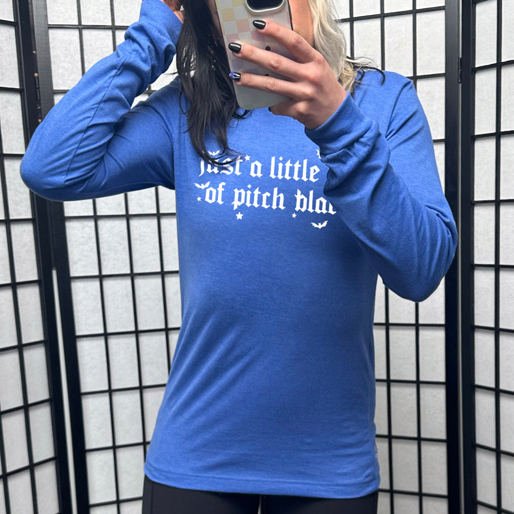 heather true royal long sleeve shirt with the words "just a little ray of pitch black" on it in a medieval font, with little bats and stars accenting the words