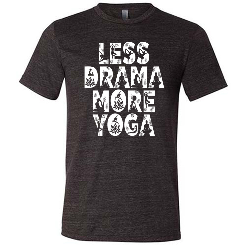 black unisex tee with the words "less drama more yoga" on it, and within each letter there are silhouettes of people doing yoga poses as well as some lotus flowers and some leaves