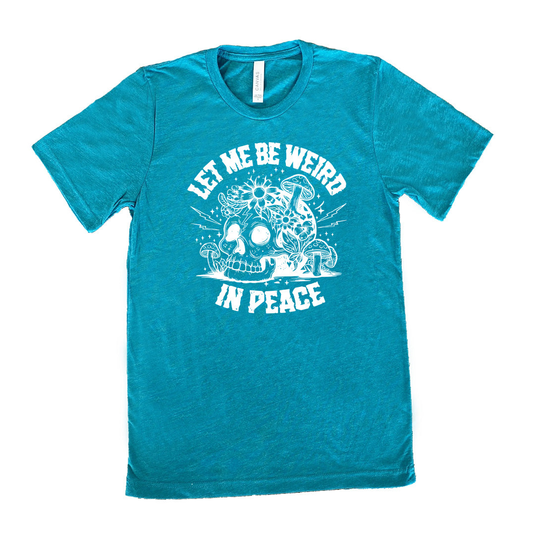 teal unisex tee with the words "let me be weird in peace" on it with the graphic of a skull on the ground with mushrooms growing on and around it, as well as flowers growing on it, surrounded by little stars and lightening bolts