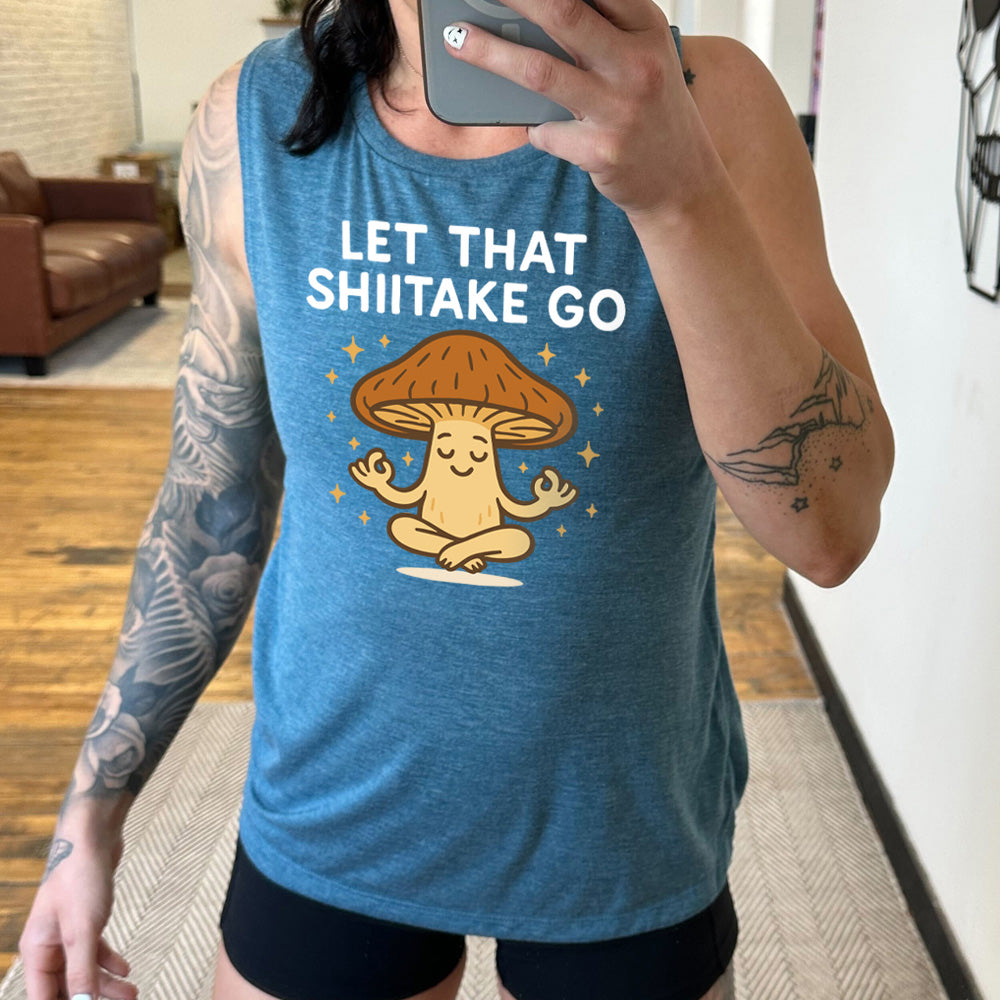 deep teal muscle tank with the words "let that shiitake go" on it and the graphic of a mushroom doing a yoga pose, surrounded by little stars