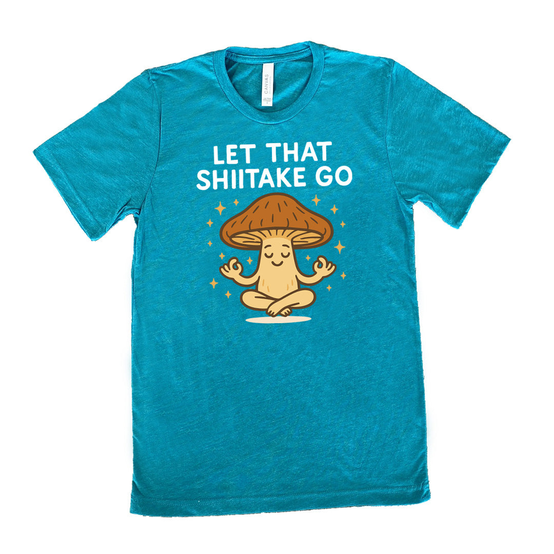 teal unisex tee with the words "let that shiitake go" on it and the graphic of a mushroom doing a yoga pose, surrounded by little stars