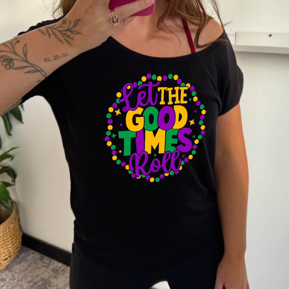 black slouchy tee with the words "let the good times roll" on it, with a few little stars around, all within a ring of mardi gras beads