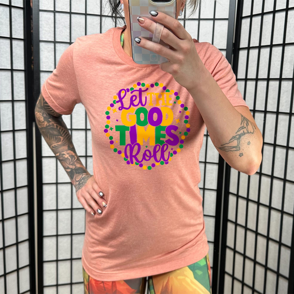 sunset unisex tee with the words "let the good times roll" on it, with a few little stars around, all within a ring of mardi gras beads