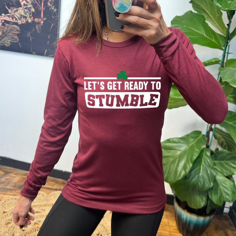 heather cardinal long sleeve with the words "let's get ready to stumble" on it, with one little shamrock graphic, and the word "stumble" in a rectangular block, and the letters leaning in different directions