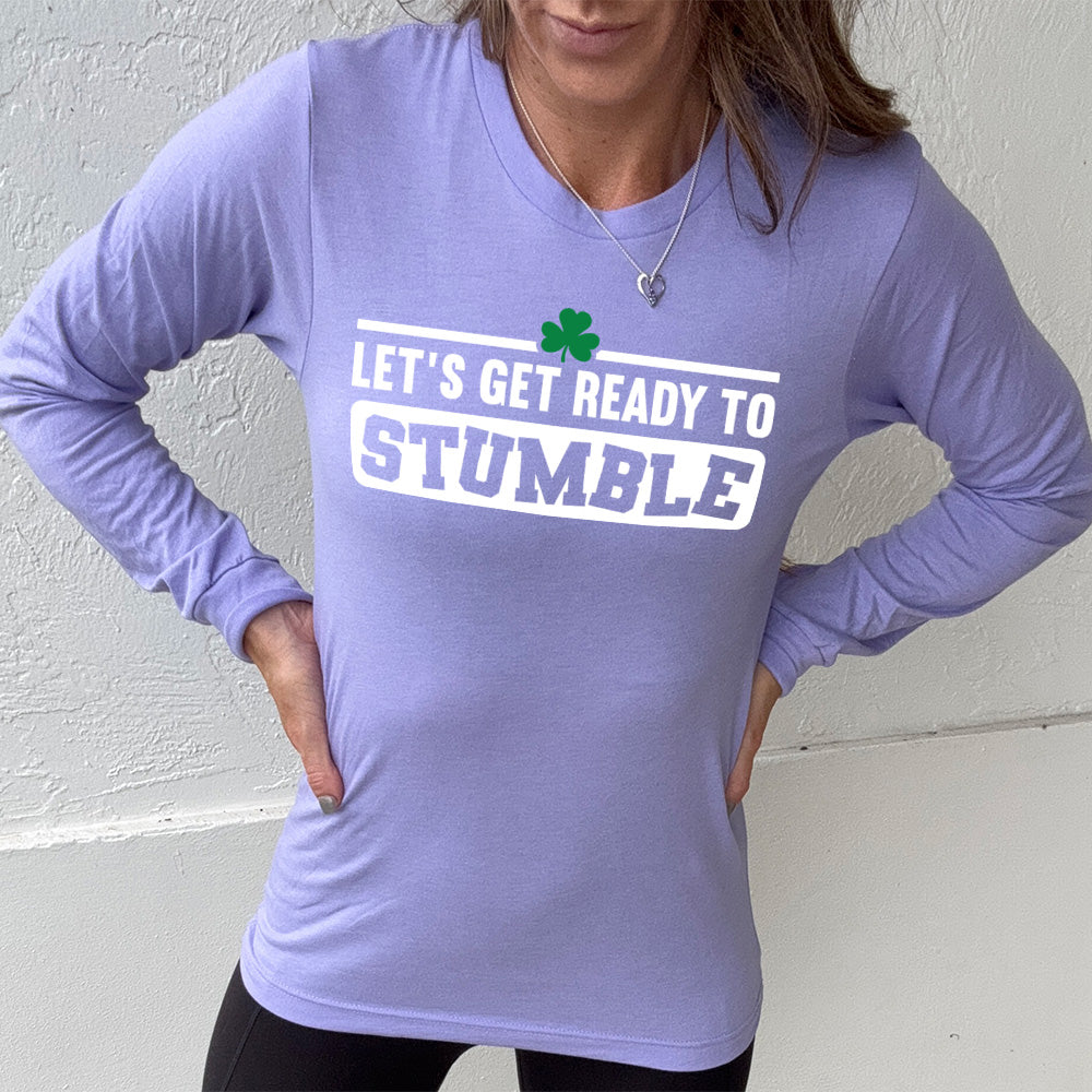 heather dark lavender long sleeve with the words "let's get ready to stumble" on it, with one little shamrock graphic, and the word "stumble" in a rectangular block, and the letters leaning in different directions