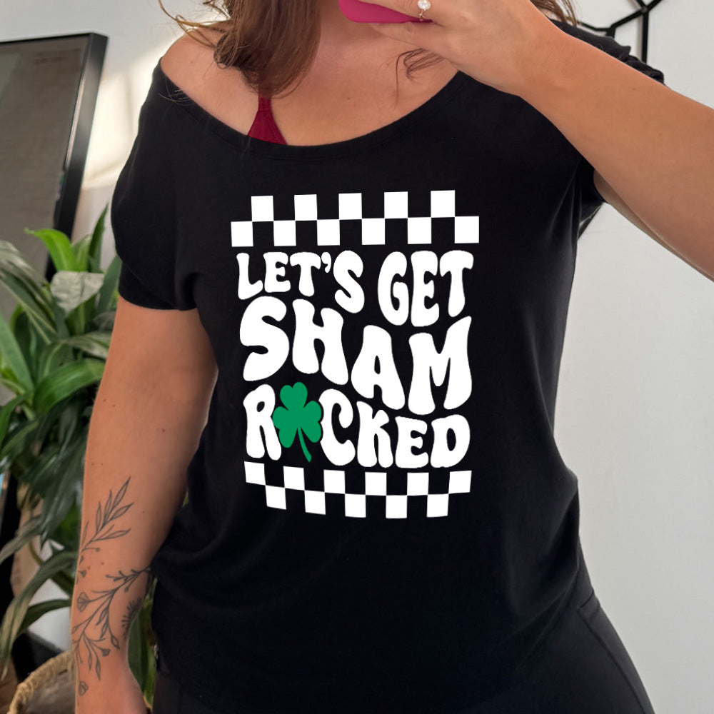 black slouchy tee with the words "let's get shamrocked" on it, with a shamrock graphic replacing the "o" of "rocked", and a checkerboard border on top and bottom of the words