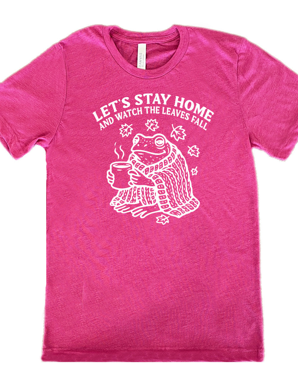 berry unisex tee with the words "let's stay home and watch the leaves fall" on it, and the graphic underneath of a frog, wrapped in a blanket, holding a mug of steaming beverage, with five leaves arching over it