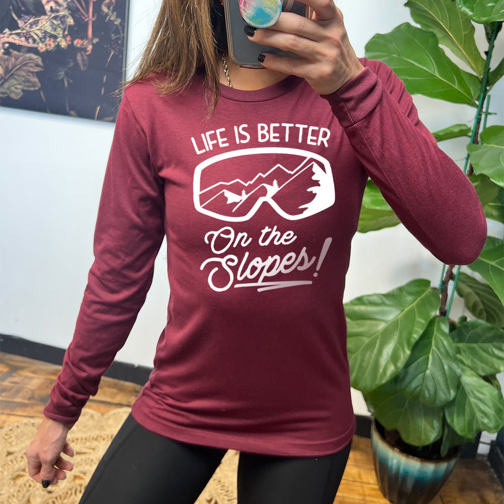 Heather cardinal long sleeve with the words "Life is better on the slopes!" with the image of snow goggles and a reflection of the slopes in them