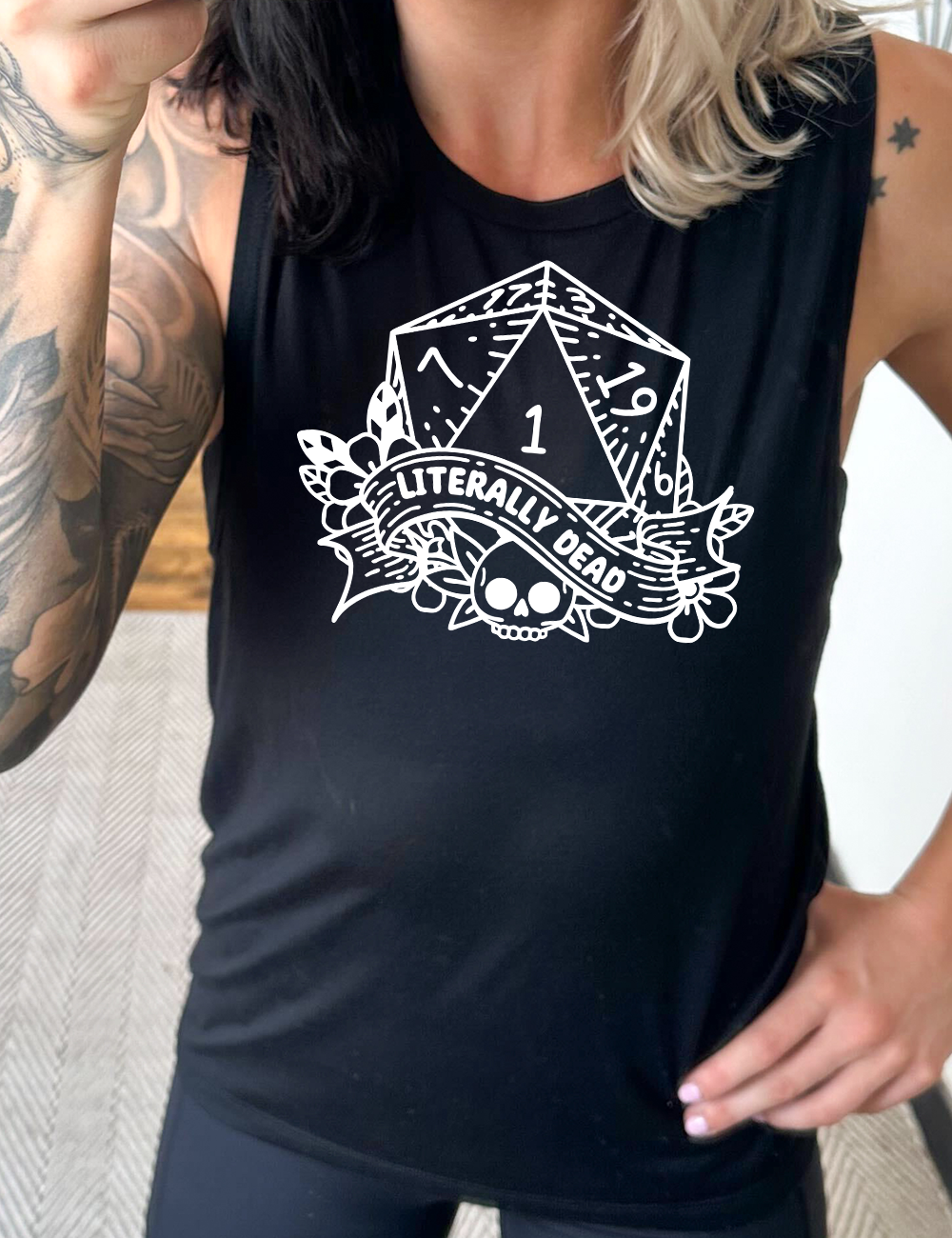 black muscle tank with the graphic of a dungeons and dragons die (with the numbers 17, 3, 7, 1, 19, and 6 showing) above a skull among flowers, and a small banner reading "literally dead"