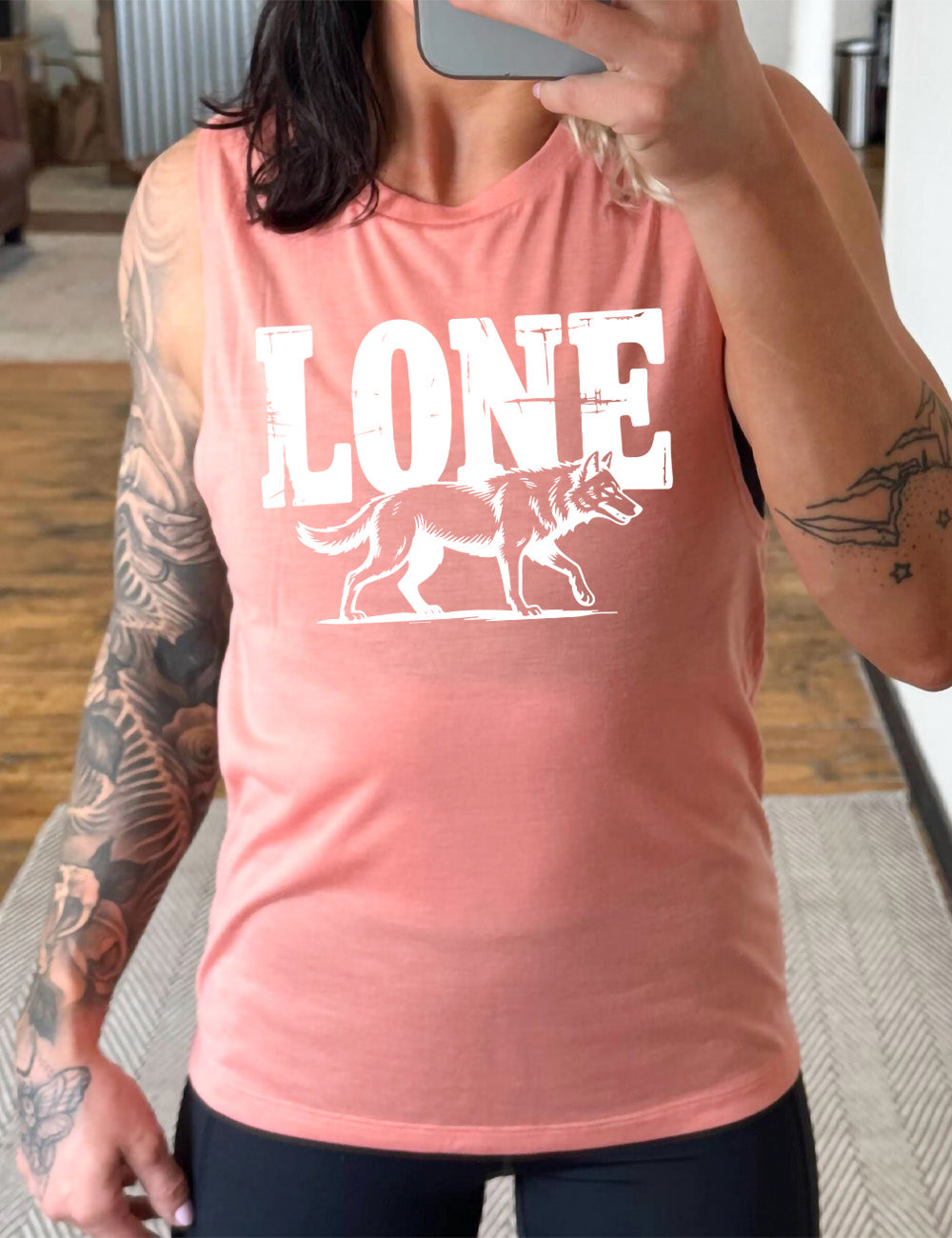 peach muscle tank with the large all caps word "lone" on it, with a wolf graphic underneath