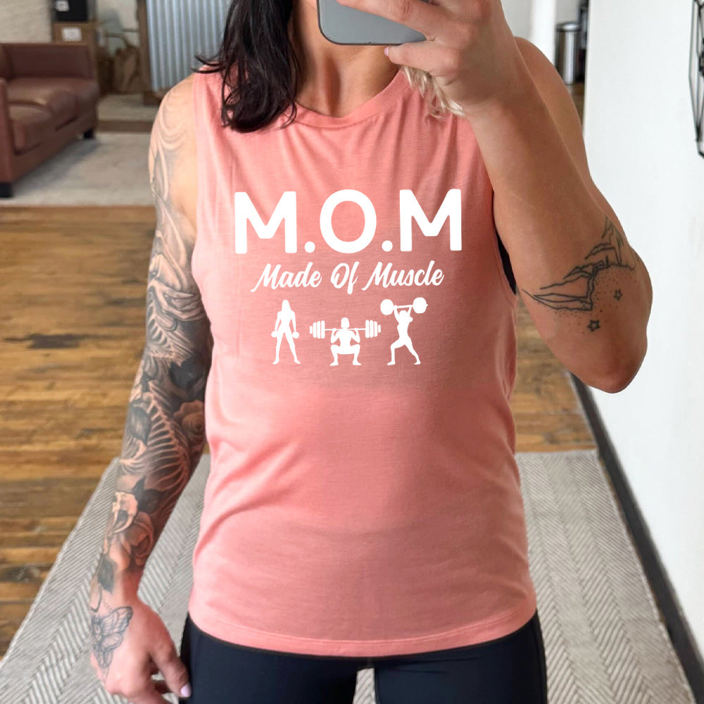 peach muscle tank with the word "mom" in large letters as an acronym for the smaller words below it saying "made of muscle", and the graphic of three female silhouettes holding weights