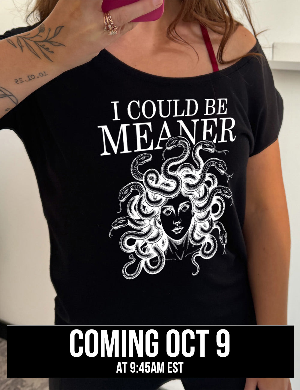 black slouchy tee with the graphic of snake-haired medusa, with the words above it saying "I could be meaner" Coming October 9th