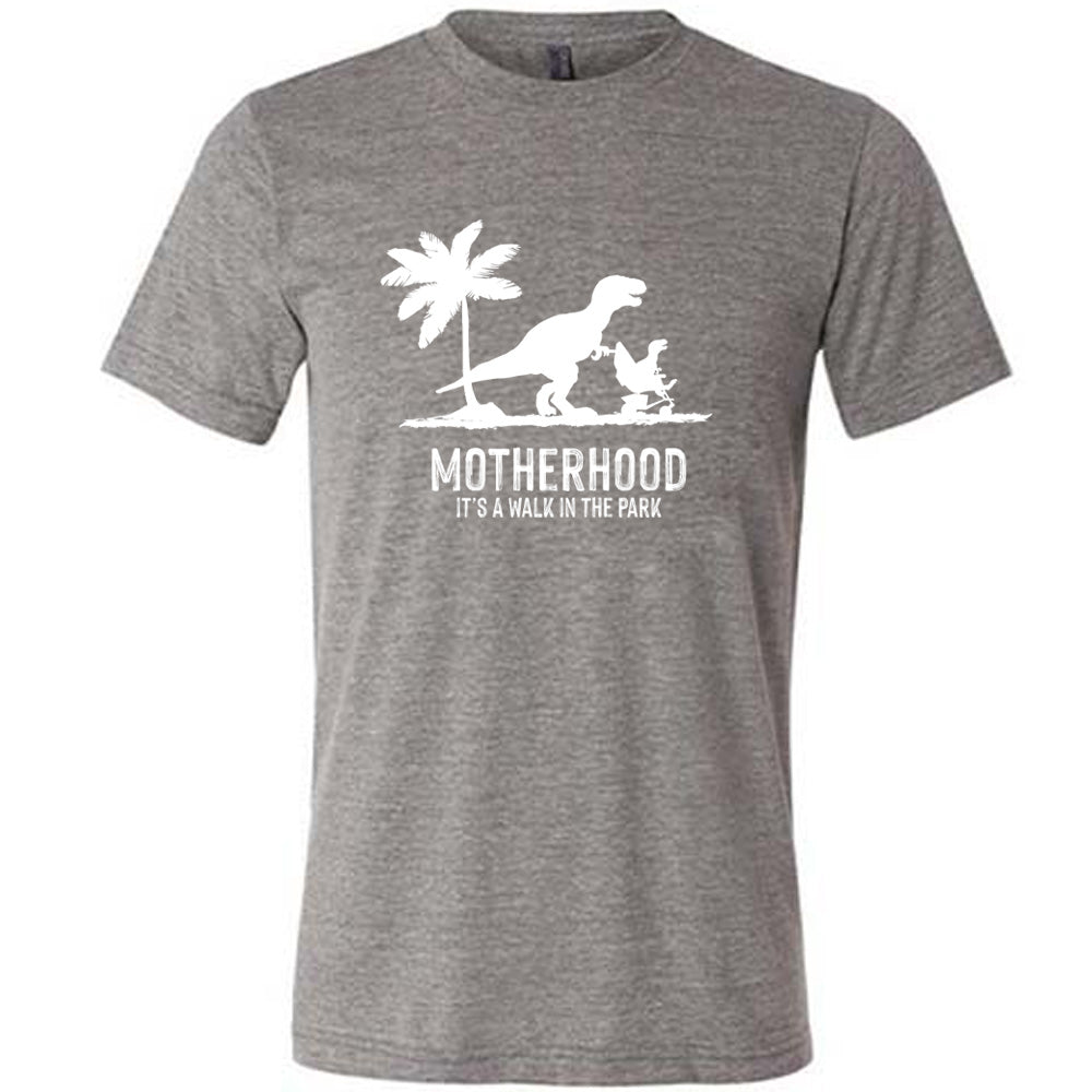 Grey colored shirt with a mother and child dinosaur graphic on it that says "Motherhood, Its a Walk in the Park"