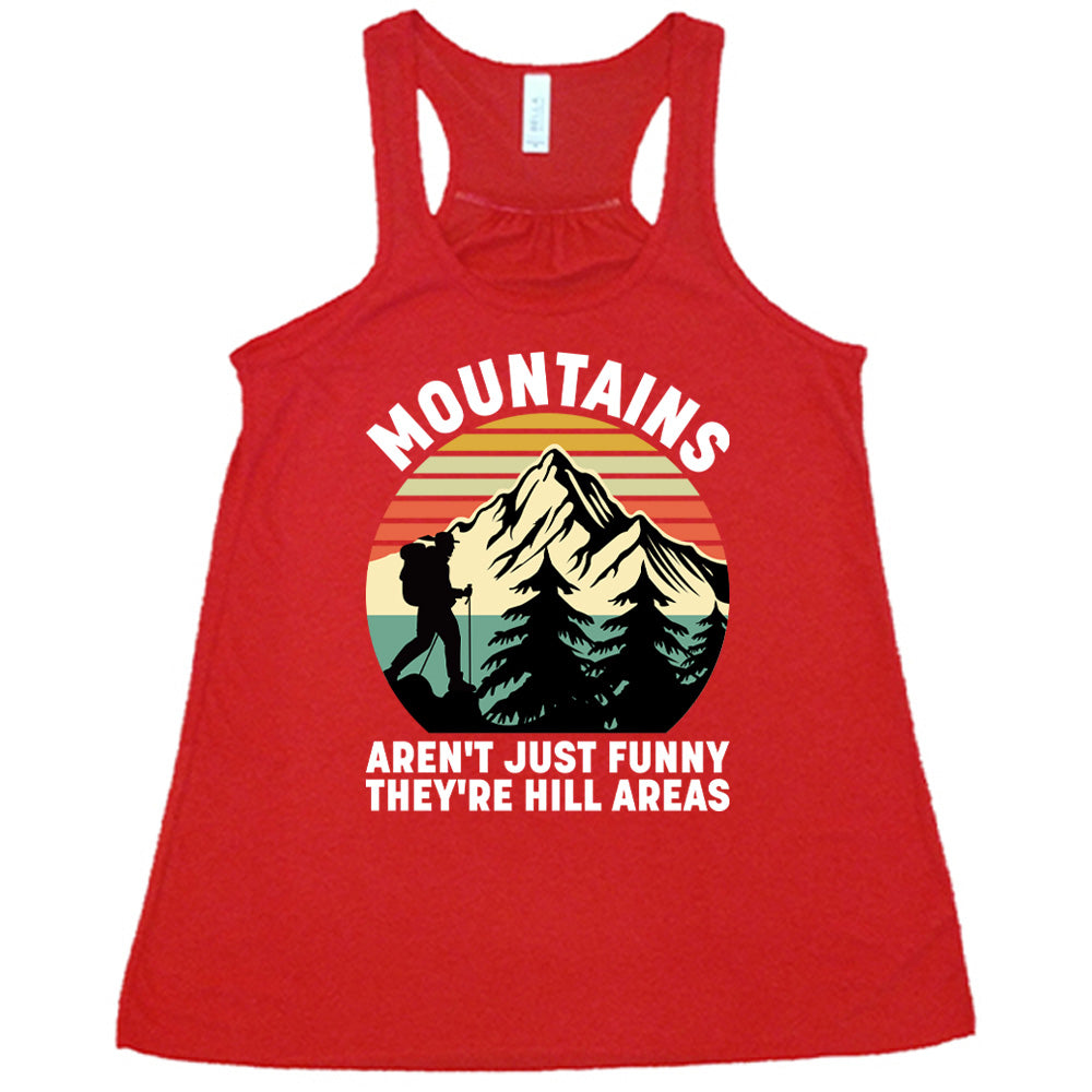 red flowy tank with the words "mountains aren't just funny they're hill areas" on it, with the graphic of a mountain, trees, a colorful sky, and the silhouette of a hiker