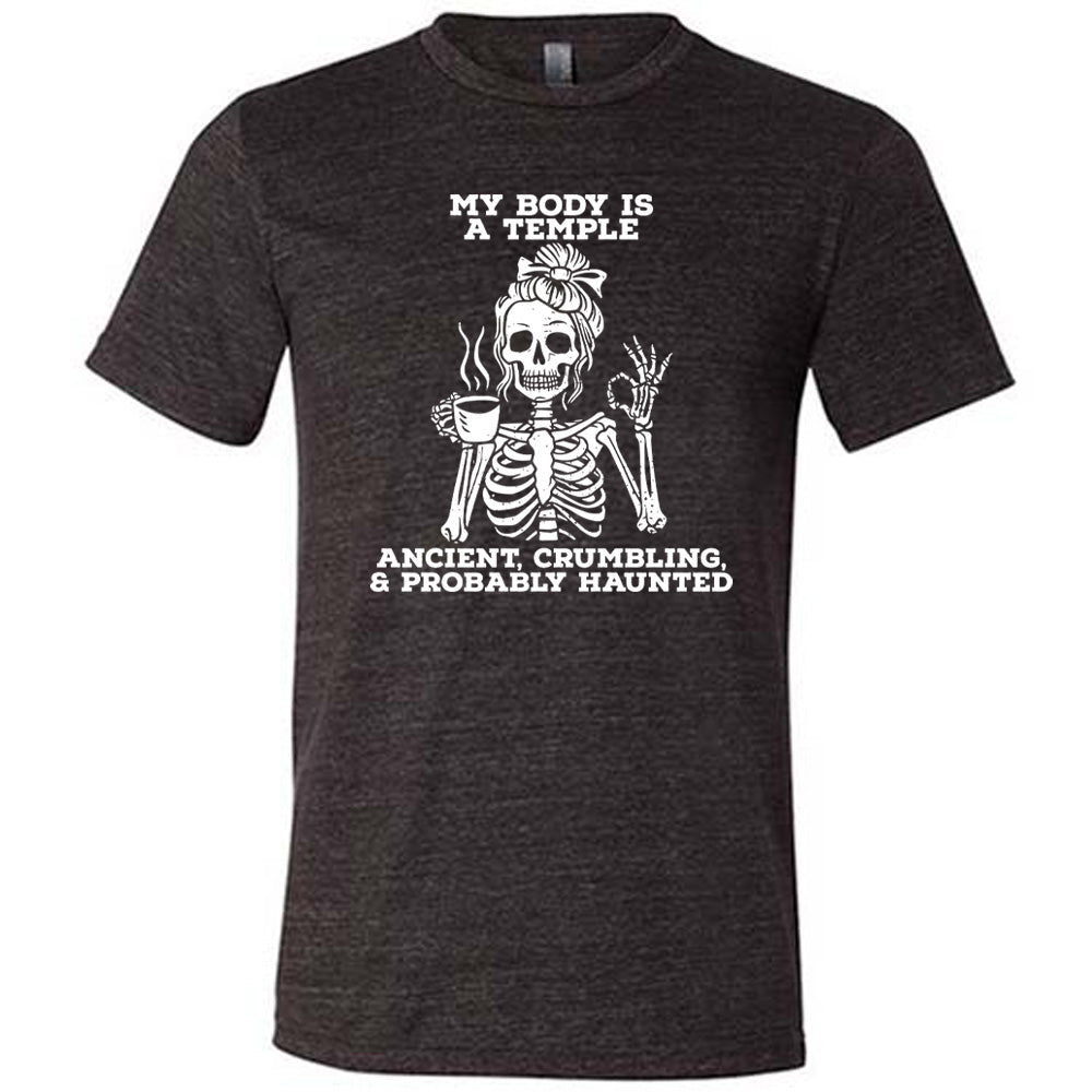 black unisex tee with the words "My Body Is a Temple Ancient, Crumbling, & Probably Haunted" on it, with the graphic of a skeleton with its hair in a bow, with one hand holding steaming coffee, and the other giving the OK symbol