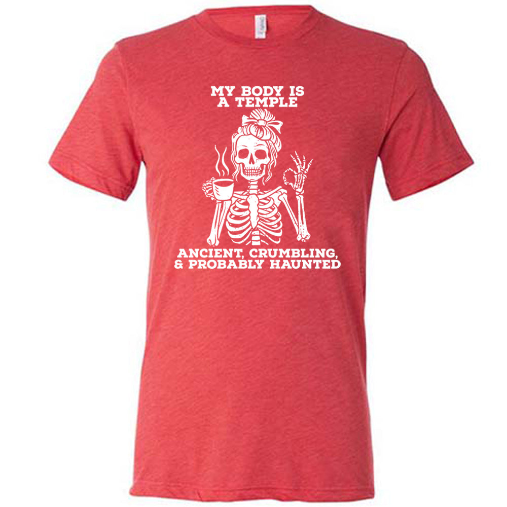 red unisex tee with the words "My Body Is a Temple Ancient, Crumbling, & Probably Haunted" on it, with the graphic of a skeleton with its hair in a bow, with one hand holding steaming coffee, and the other giving the OK symbol