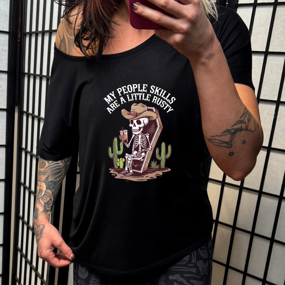 black slouchy shirt with a skeleton sitting in a coffin graphic on it that says "My People Skills Are A Little Rusty"
