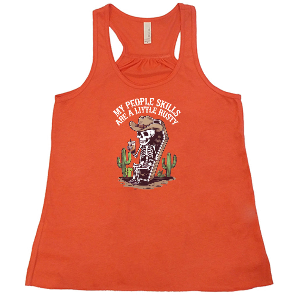 Coral colored flowy tank with a skeleton sitting in a coffin graphic on it that says "My People Skills Are A Little Rusty"