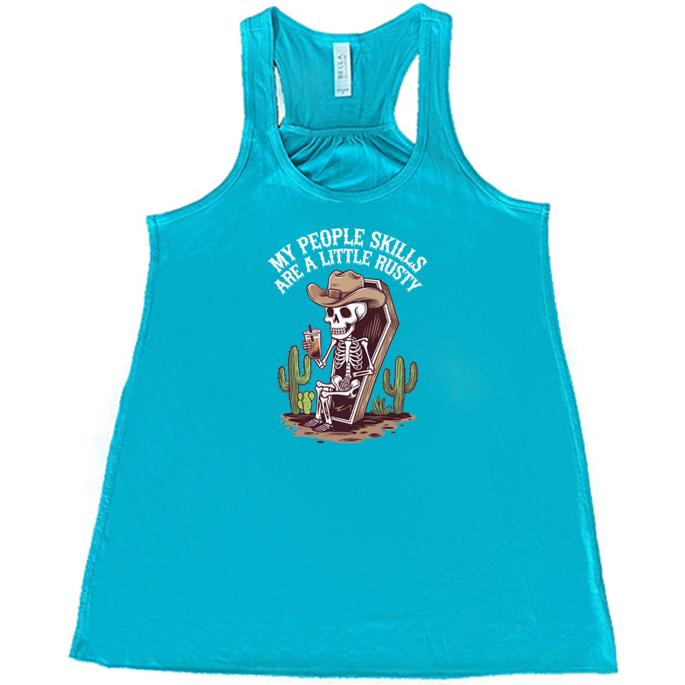 Teal colored flowy tank with a skeleton sitting in a coffin graphic on it that says "My People Skills Are A Little Rusty"
