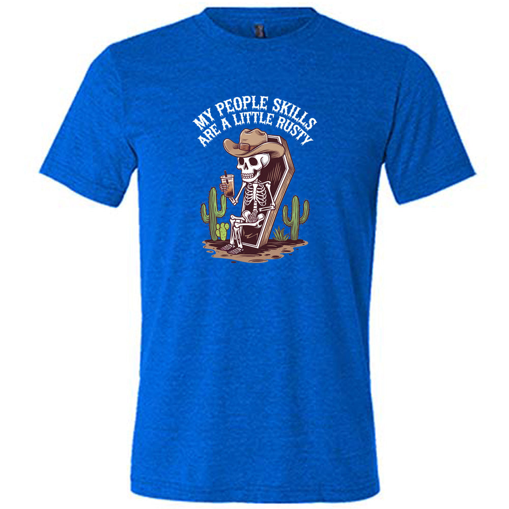 Blue colored shirt with a skeleton sitting in a coffin graphic on it that says "My People Skills Are A Little Rusty"