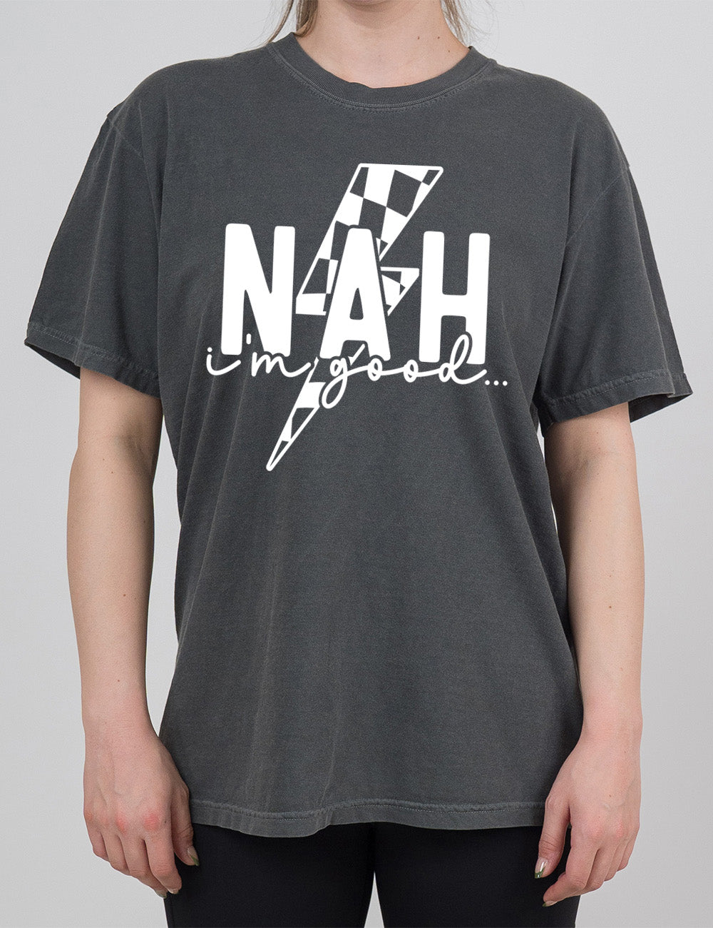 pepper modern tee with the large word "NAH" and small lowercase cursive words underneath saying "i'm good", and the graphic of a checkered lightning bolt behind the words