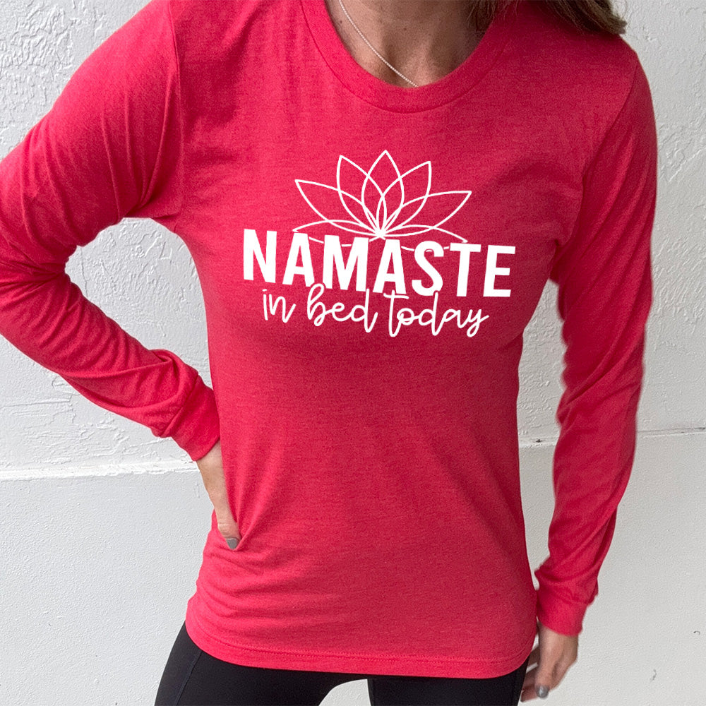Heather red long sleeve shirt with the words "Namaste in bed today" with a line art of a lotus flower above it