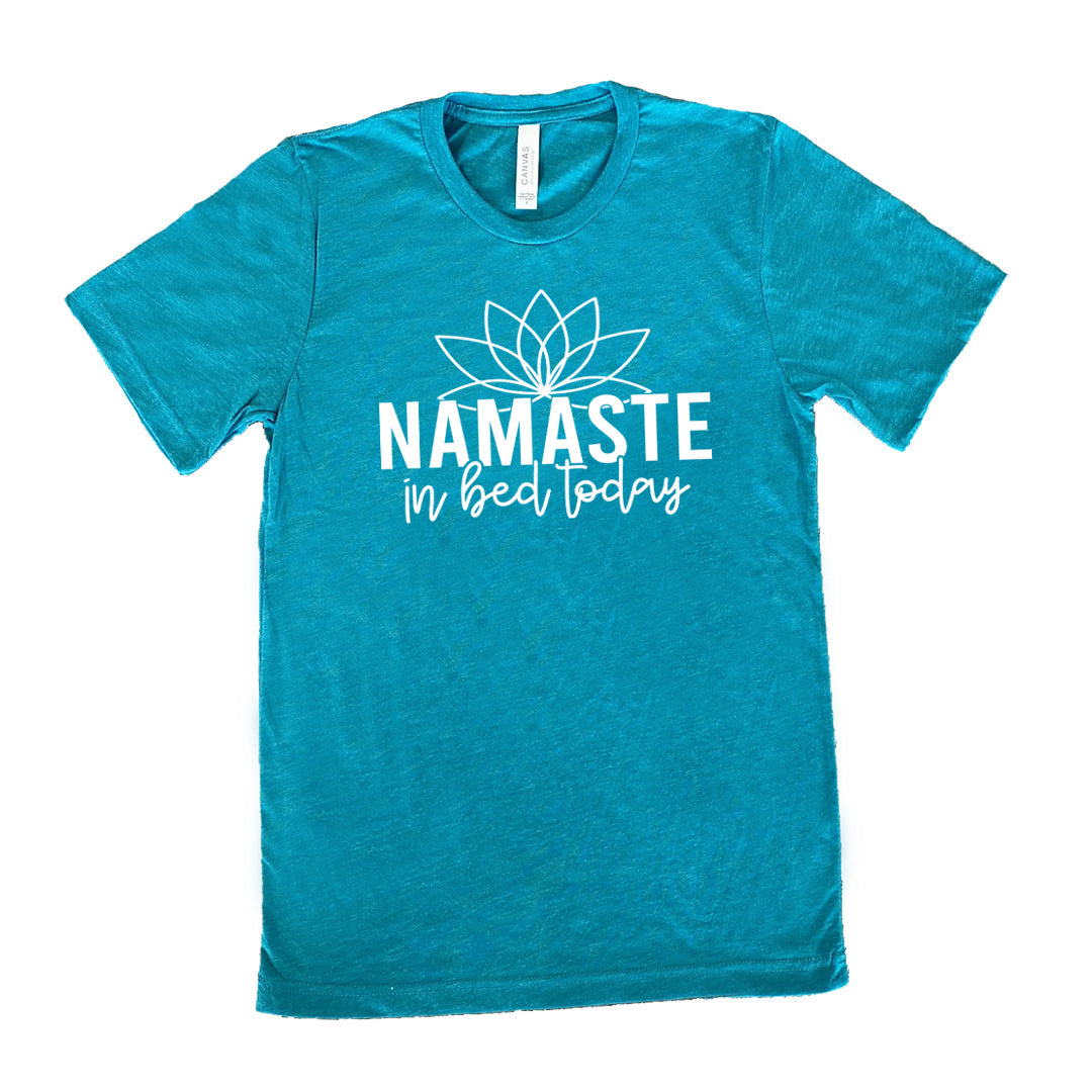 Teal unisex tee with the words "Namaste in bed today" with a line art of a lotus flower above it