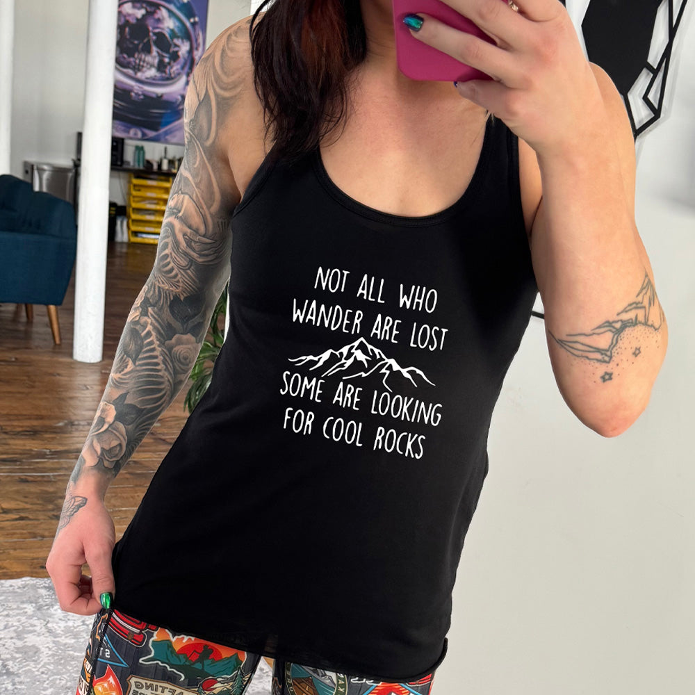 Black colored flowy tank with a mountain graphic on it that says "Not All Who Wander Are Lost Some Are Looking For Cool Rocks"