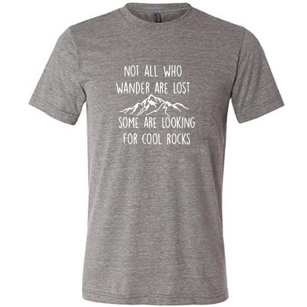 Grey colored shirt with a mountain graphic on it that says "Not All Who Wander Are Lost Some Are Looking For Cool Rocks"
