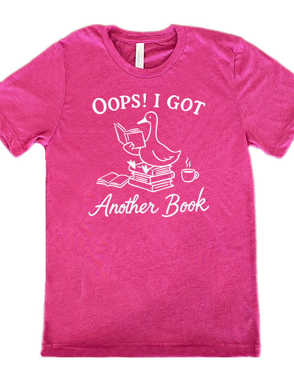 berry unisex tee with the graphic of a goose, sitting on a stack of books, reading a book, with another book open beside the stack, and a steaming cup of coffee on the other side, with the words around the graphic saying "Oops! I got another book"