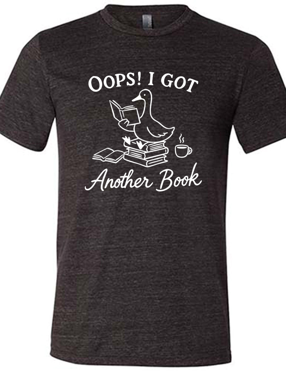 black unisex tee with the graphic of a goose, sitting on a stack of books, reading a book, with another book open beside the stack, and a steaming cup of coffee on the other side, with the words around the graphic saying "Oops! I got another book"