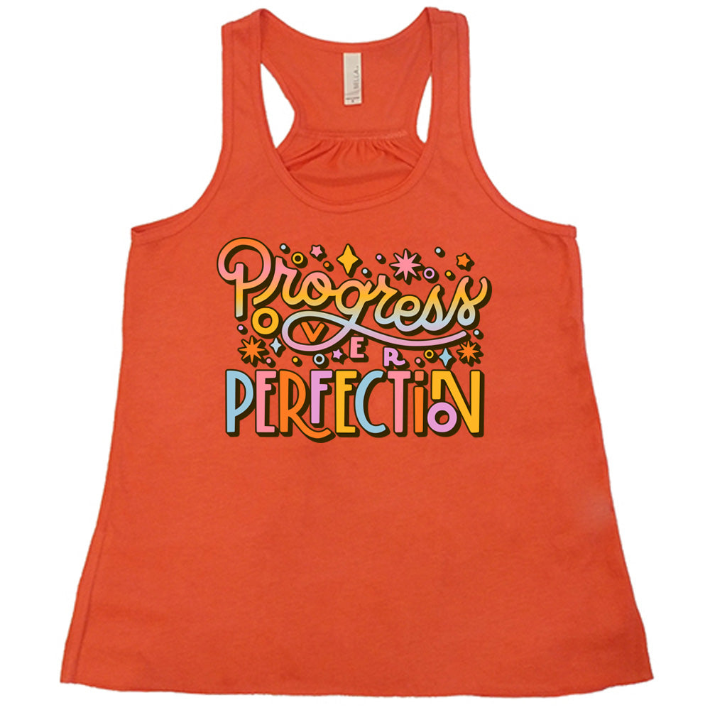 Coral flowy tank with Progress Over Perfection written in colorful lettering, with various stars