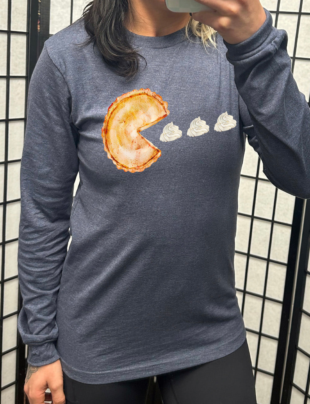 heather navy long sleeve tee with the graphic of a pumpkin pie, with the a slice taken out of it so that it looks like Pacman, heading in the direction of three dollops of whipped cream