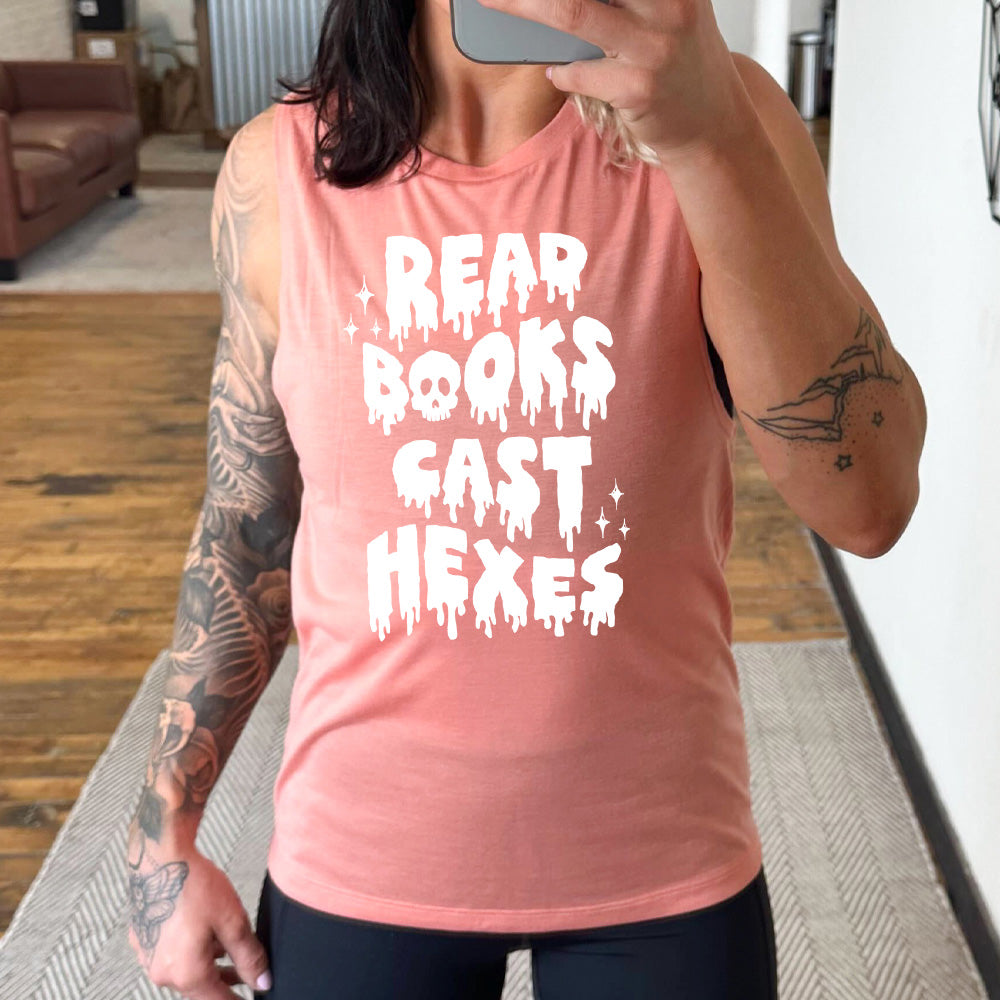 peach muscle tank with the horror-style text saying "Read Books Cast Hexes" on it, with one of the "o"s being a skull, with a few little stars