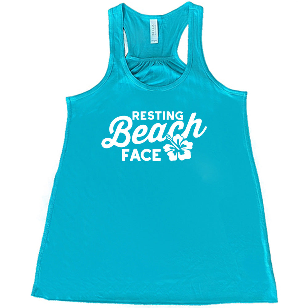 Teal colored flowy tank with a flower graphic on it that says "Resting Beach Face"