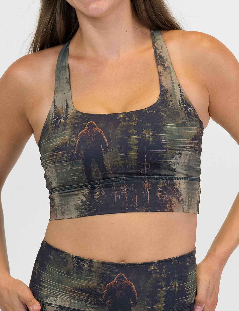 front of the bigfoot in a forest sports bra against a white background