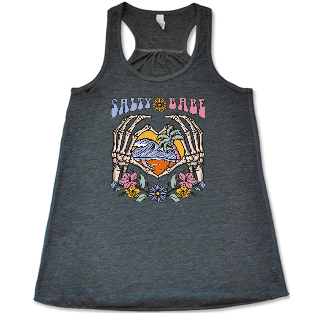 Grey colored flowy tank with a skeleton heart hands around ocean waves graphic on it that says "Salty Babe"