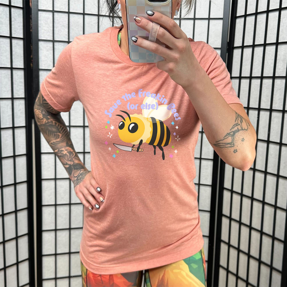 Sunset colored shirt with a bee holding a knife graphic on it that says "Save The Freakin Bees (Or Else)"