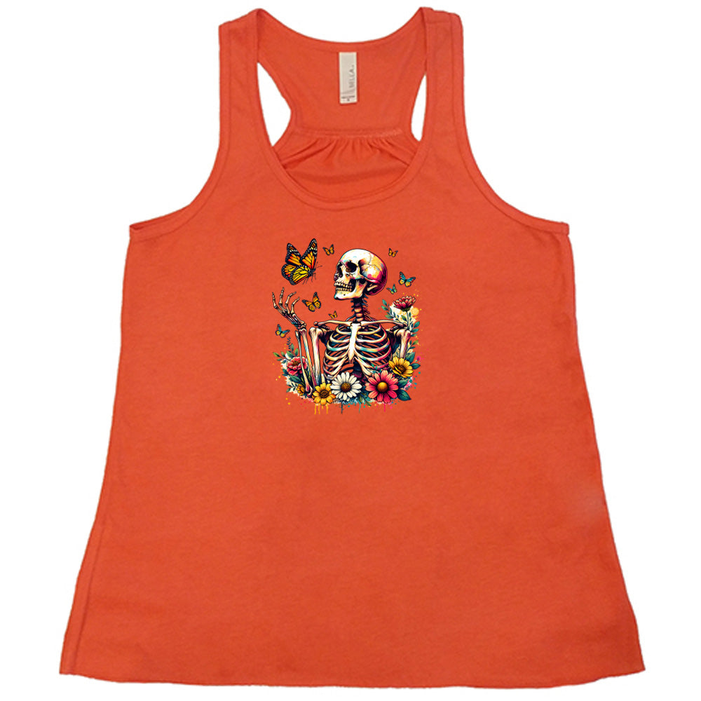 Coral colored flowy tank with a skeleton, butterflies, and flowers graphic on it