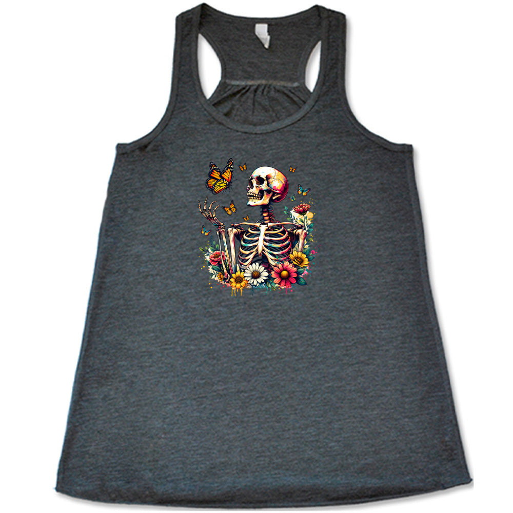 Grey colored flowy tank with a skeleton, butterflies, and flowers graphic on it