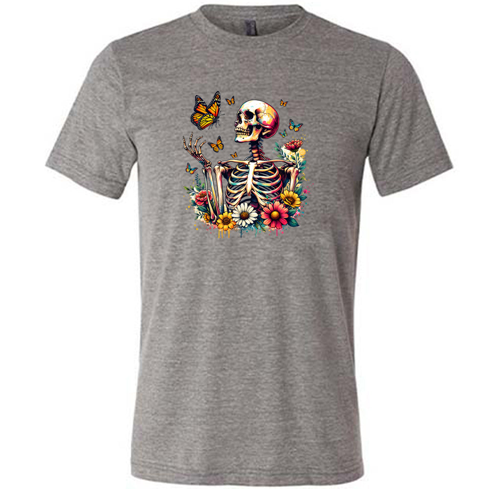 Grey colored shirt with a skeleton, butterflies, and flowers graphic on it