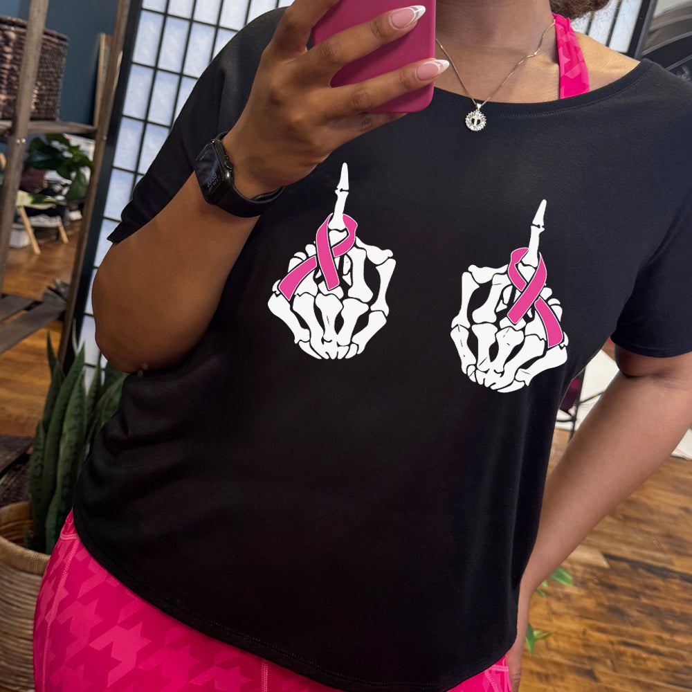 Person wearing a black t-shirt with skeleton hand designs and pink ribbons, taking a mirror selfie.