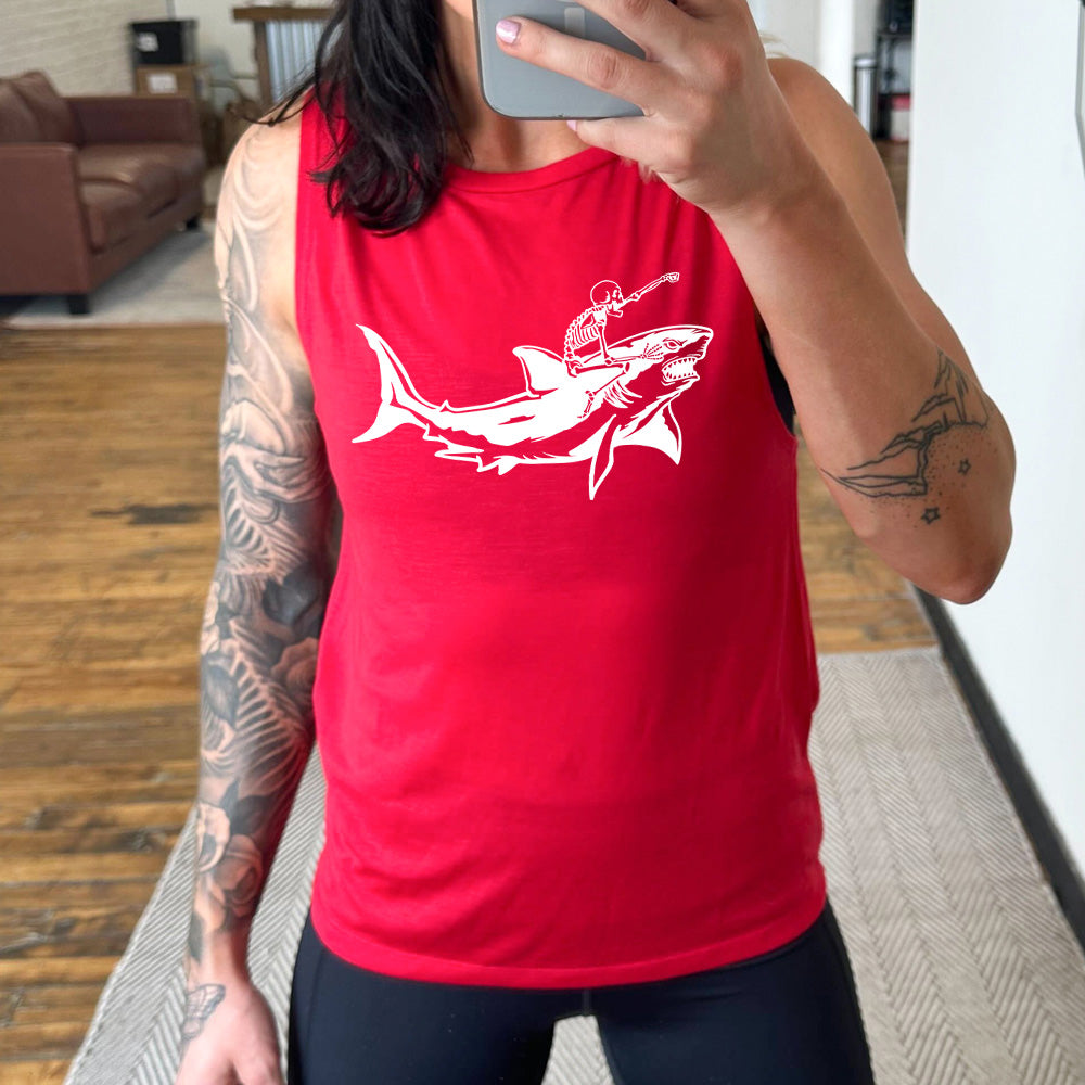 red muscle tank with the graphic of a skeleton, with its fist pointing onwards and its mouth open, riding a shark, who has a fierce expression