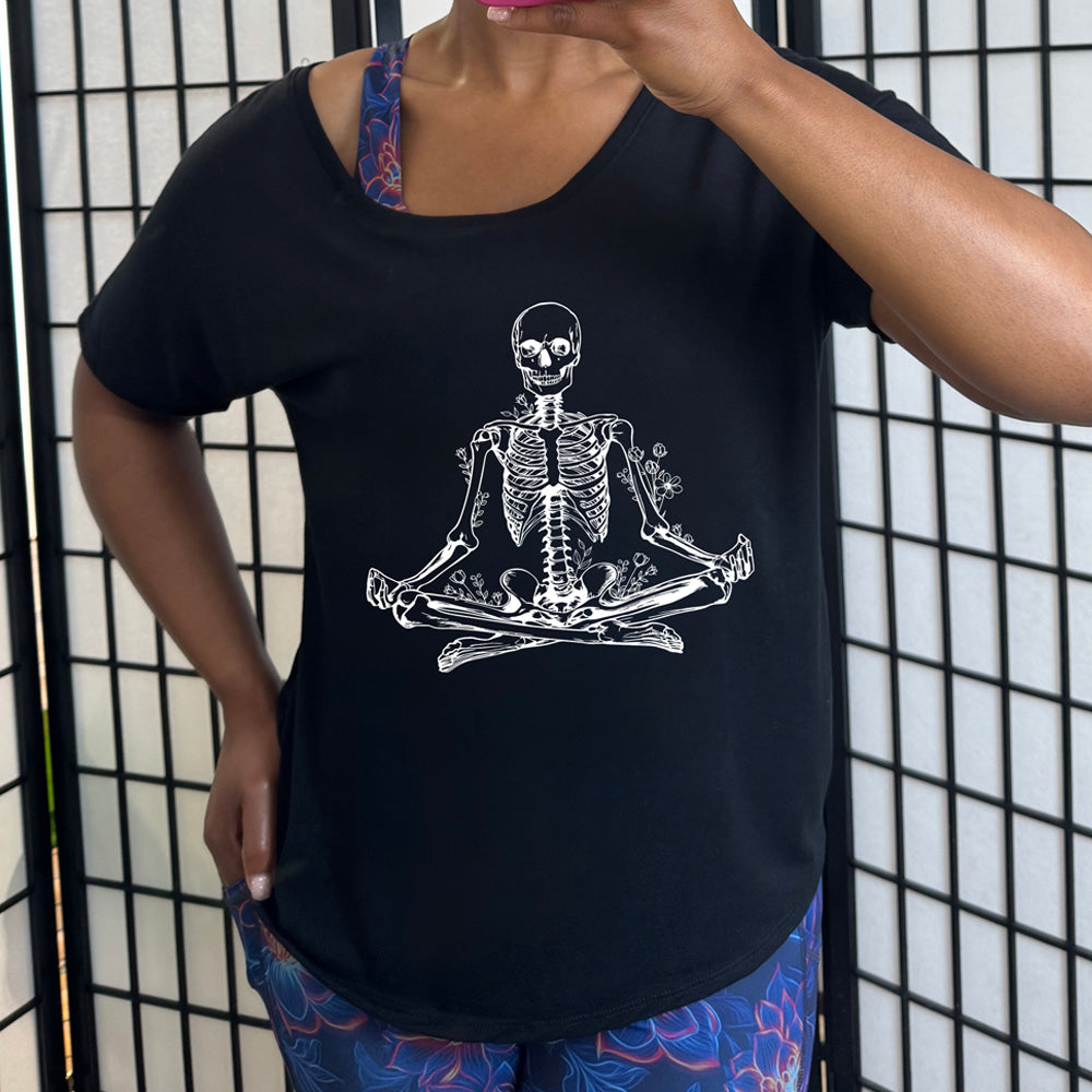 Black slouchy shirt with a graphic of a skeleton doing a yoga pose, with some flowers growing out of different place on the body