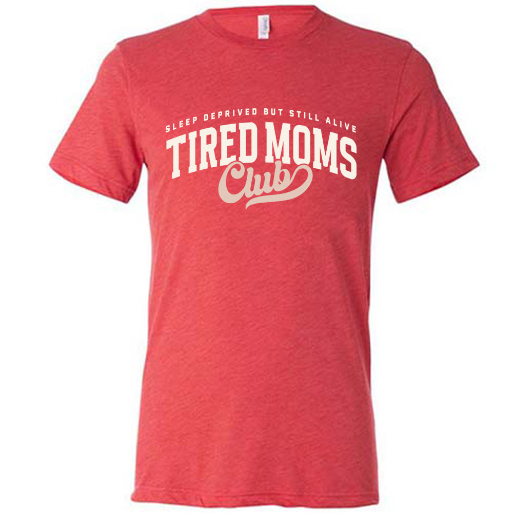 red unisex tee with the words "sleep deprived but still alive" in smaller letters, and "tired moms club" in large letters